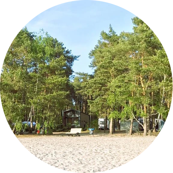Blick auf den Campingplatz zwischen Bäumen und mit einem Sandstrand